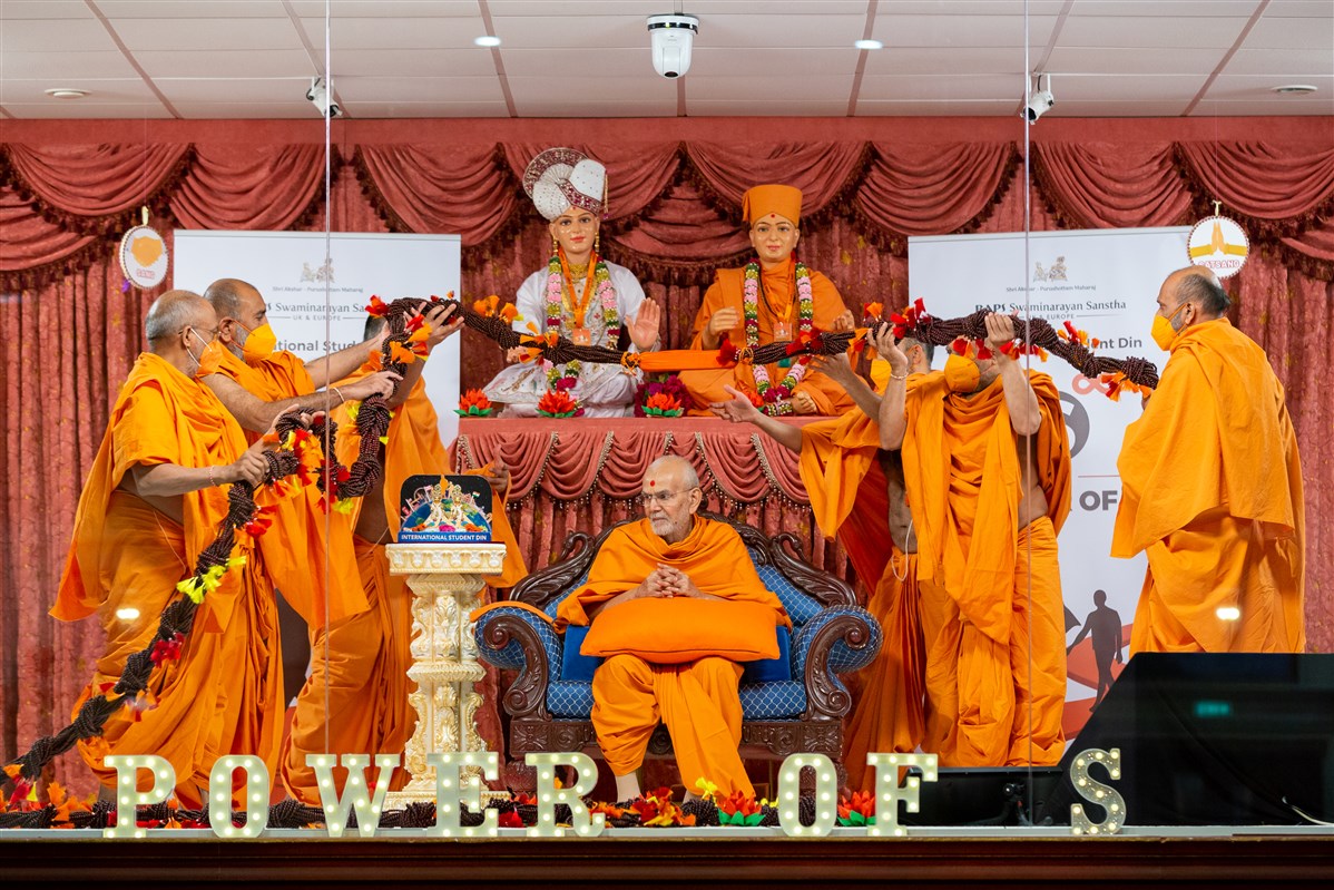 Swamis honour Swamishri with a decorative garland made from malas