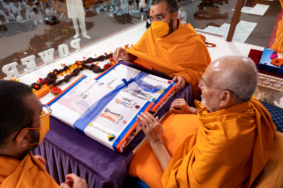 Tyagratnadas Swami and Yogikirtandas Swami present Swamishri a decorative card from the students