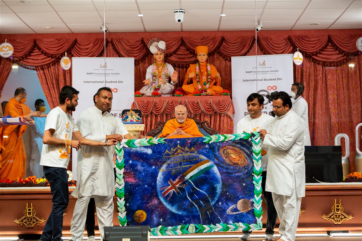 Volunteers present Swamishri with a decorative shawl