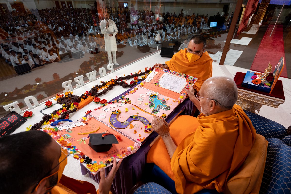 Swamishri observes the card inviting him to the evening programme
