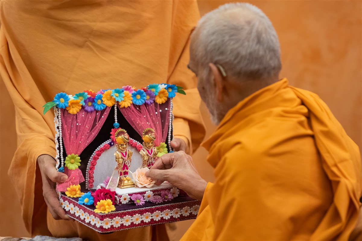 Swamishri offers a rose to Shri Harikrishna Maharaj and Shri Gunatitanand Swami Maharaj