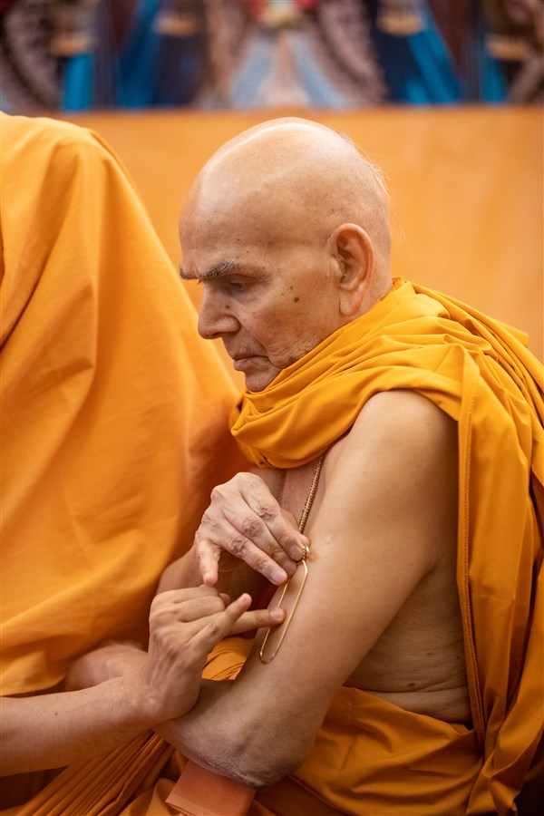 Swamishri applying a tilak on his arm