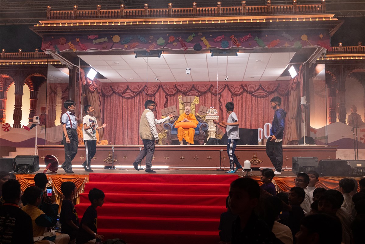 Swamishri listens attentively to the unfolding drama as the main characters in the musical continue their adventure in the chocolate wonderland