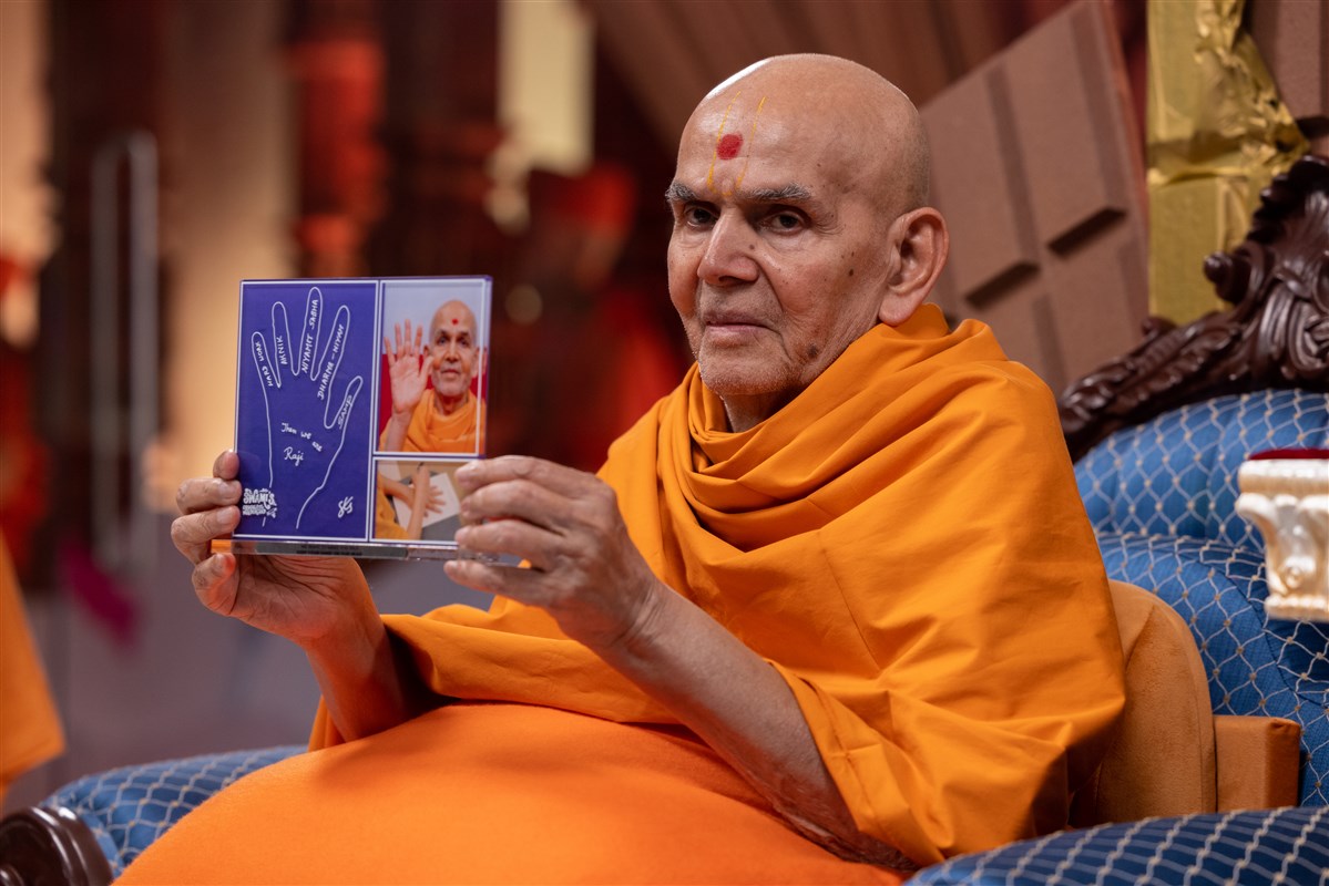 Swamishri presents a memento for the children that summarises the five values from the programme that can help them earn success and rajipo in life