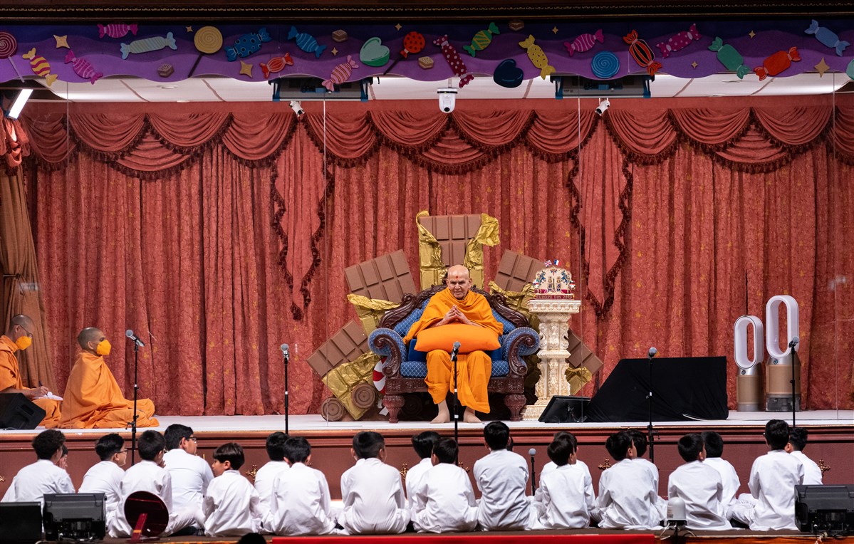 Swamishri folds his hands as young children sing a prayer before him