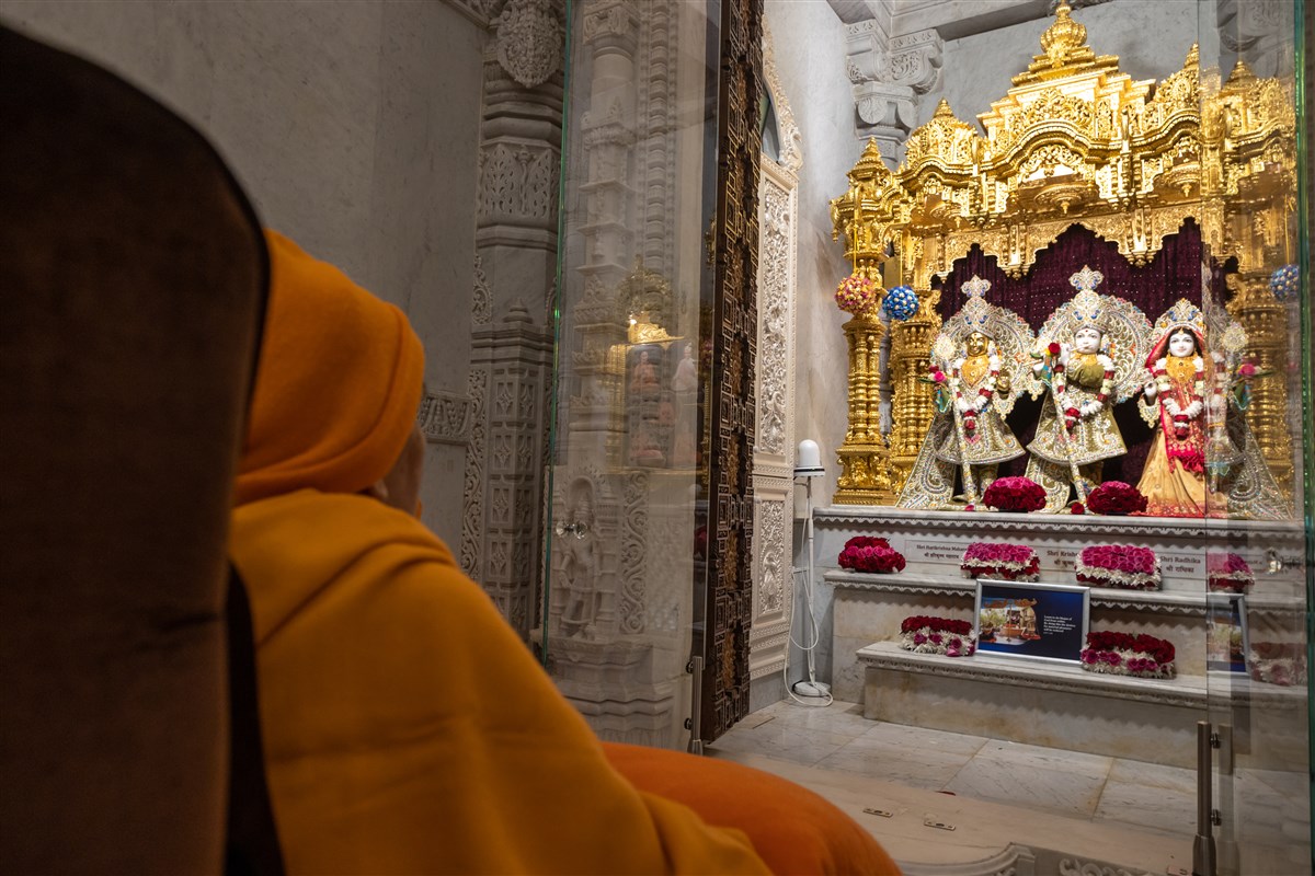 Swamishri engrossed in the darshan of Shri Harikrishna Maharaj and Shri Radha-Krishna Bhagwan