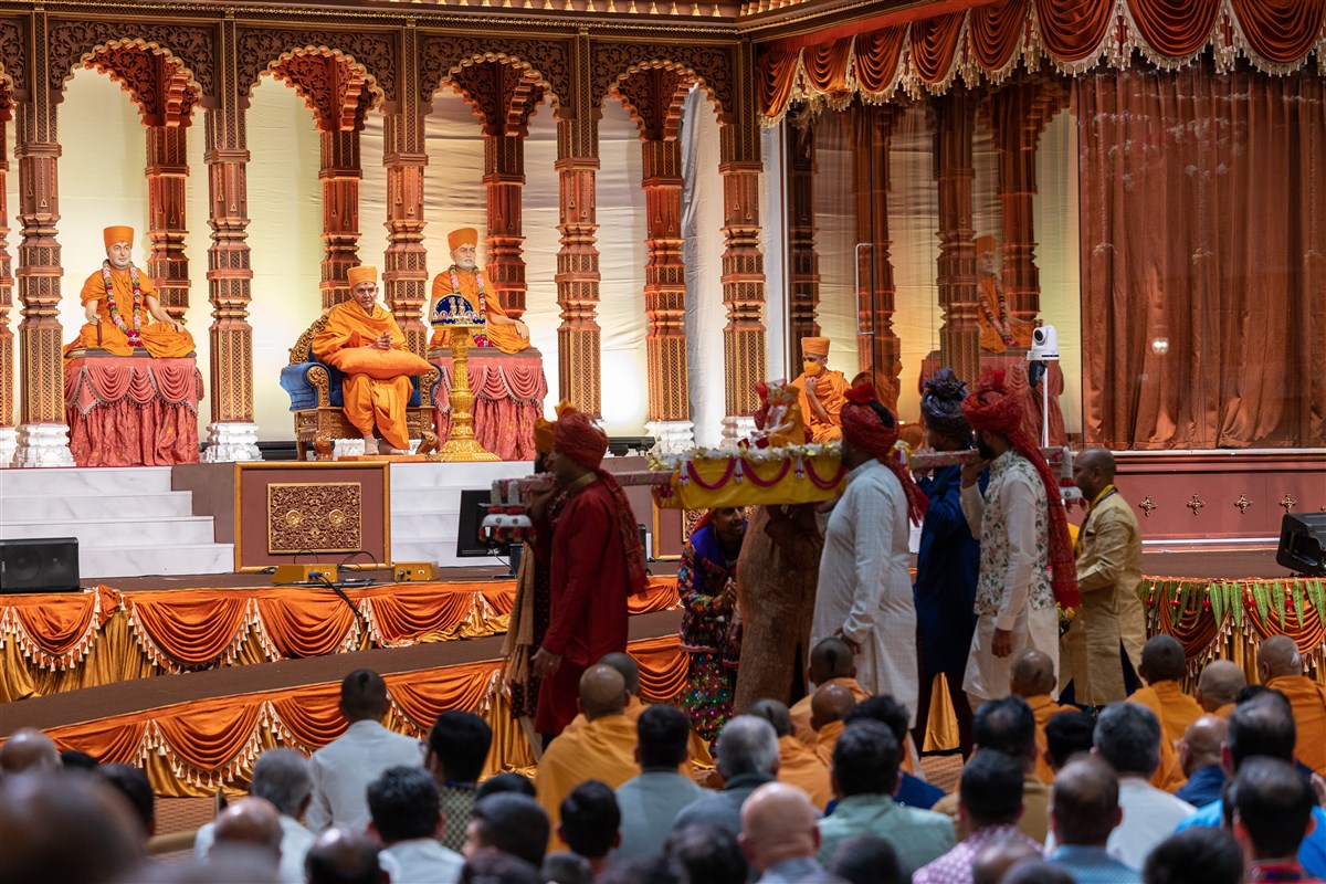 Swamishri looks on as murtis of the Guru Parampara are carried into the assembly