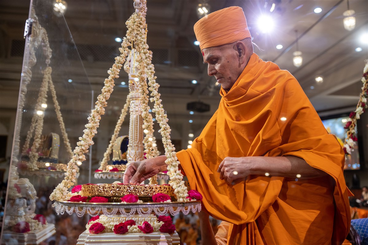 Swamishri places a devotional offering as a part of the tula ceremony
