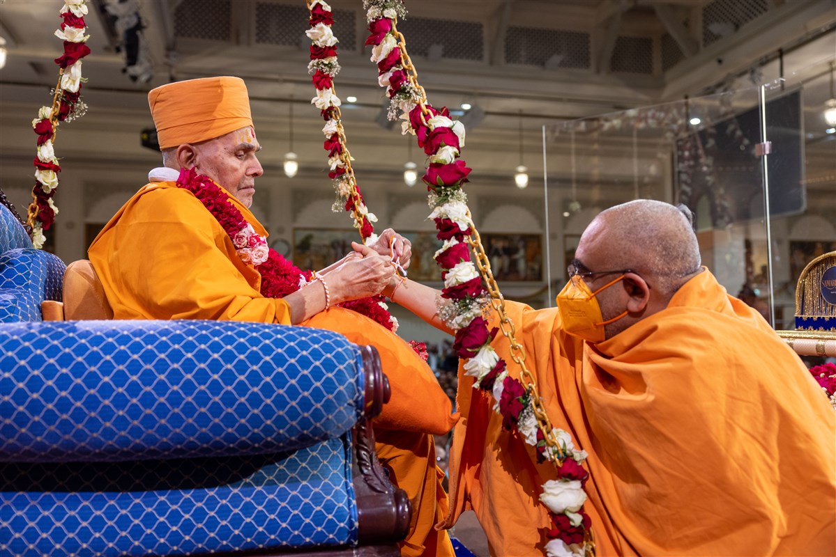 Swamishri ties a nadachhadi on Yogvivekdas Swami's wrist
