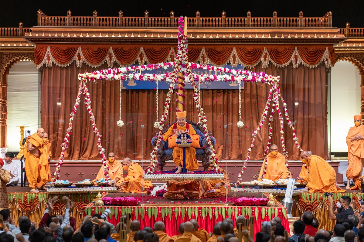 Swamishri and Thakorji are showered with flower petals as the scale rises