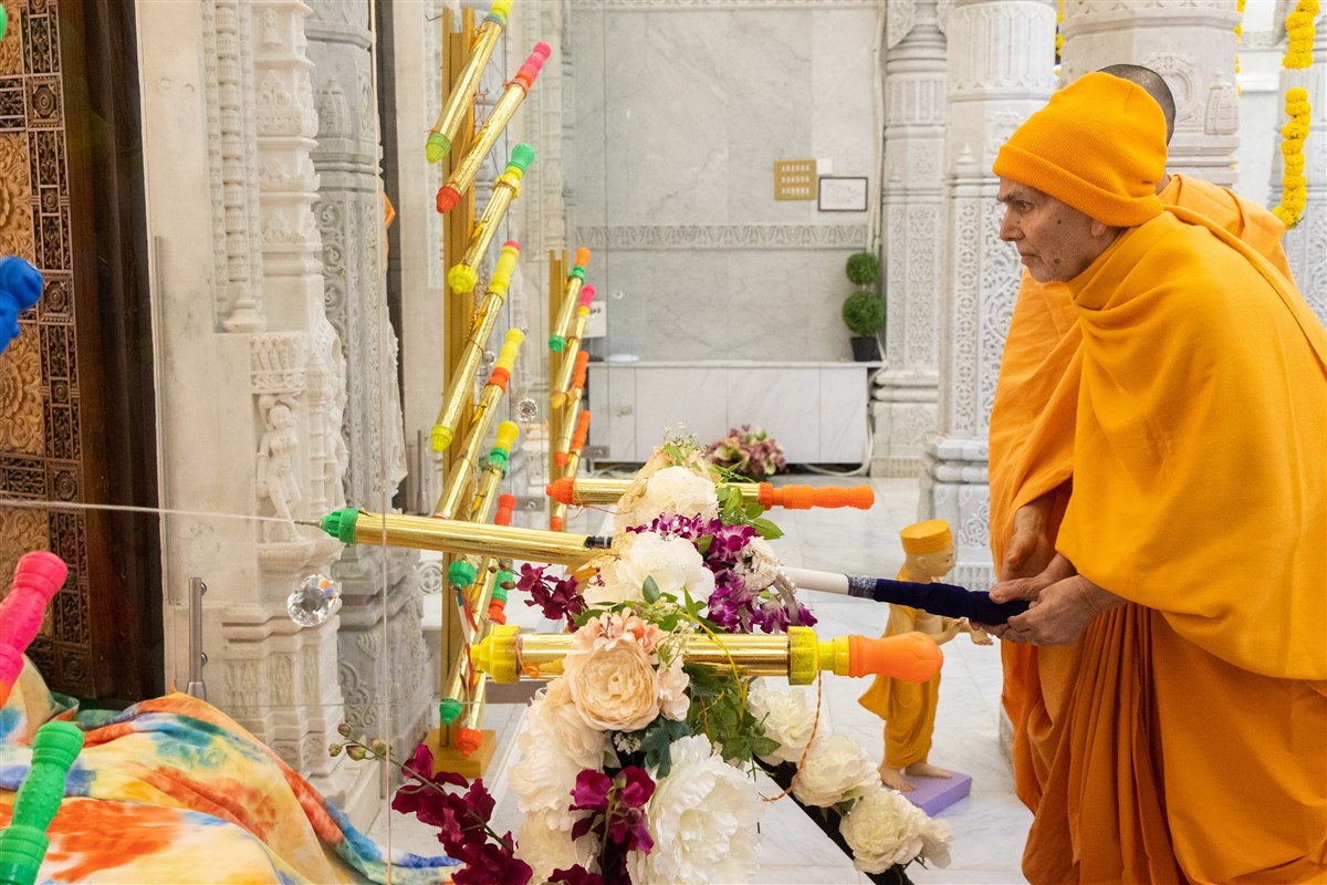Swamishri spraying Thakorji with coloured water