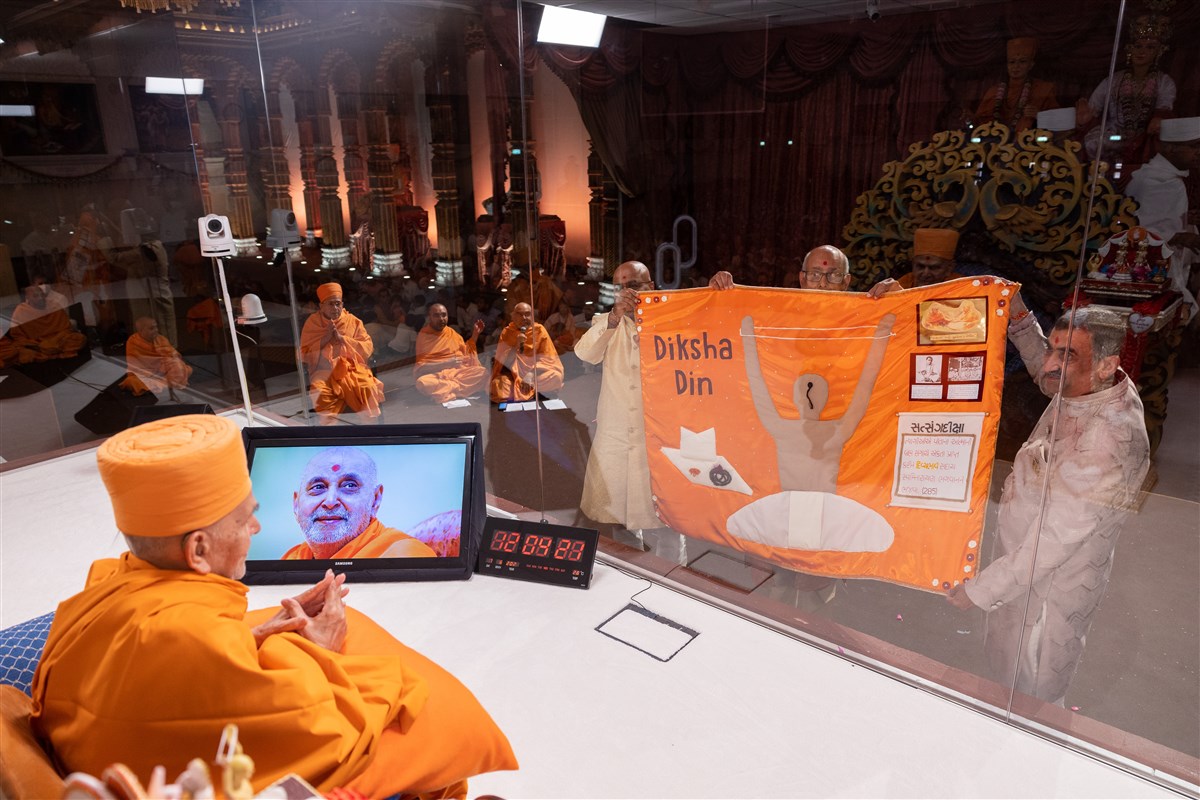 The purvashram fathers of the new parshads present a decorative shawl to Swamishri