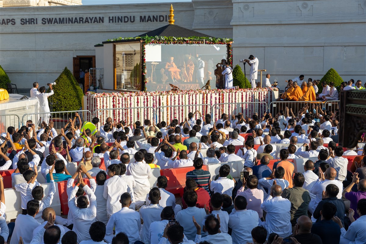 Devotees welcome Swamishri with folded hands