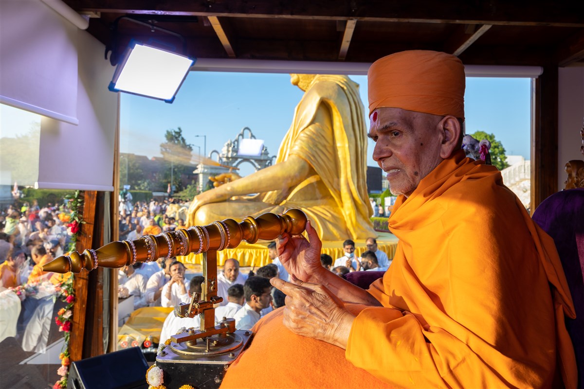 Swamishri controls the nozzle to spray swamis and devotees with coloured water