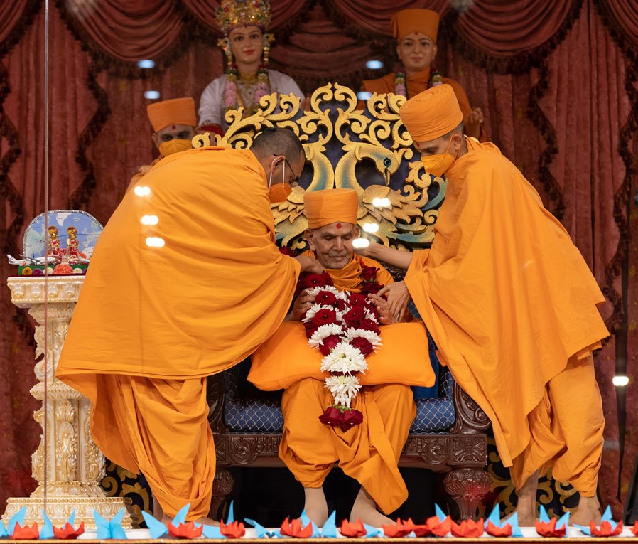 Brahmanayandas Swami and Uttamyogidas Swami honour Swamishri with a garland of fresh flowers