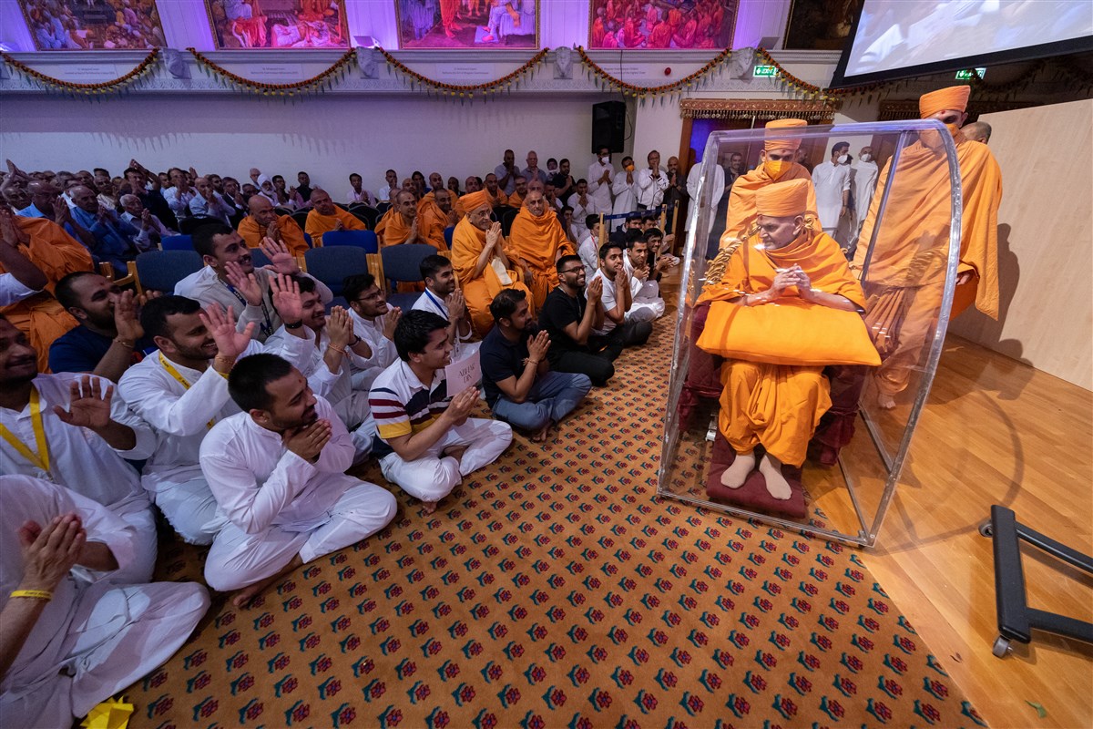 Swamishri blesses the devotees as he departs from the assembly hall