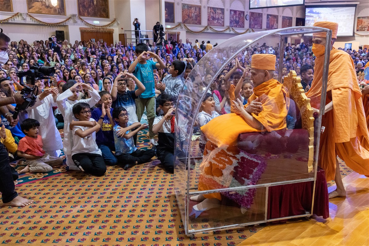 Swamishri interacts with children as he departs from the assembly hall