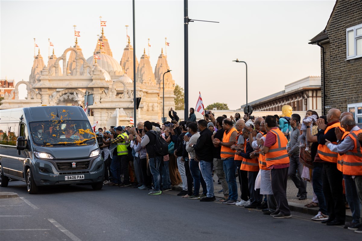 Hundreds of devotees line the road for a final glimpse of Swamishri