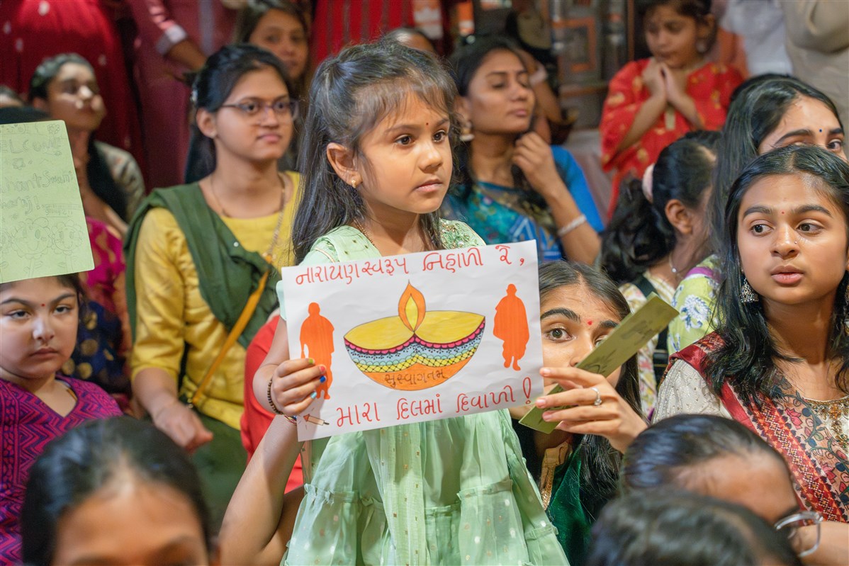 A child displays a handmade welcome poster
