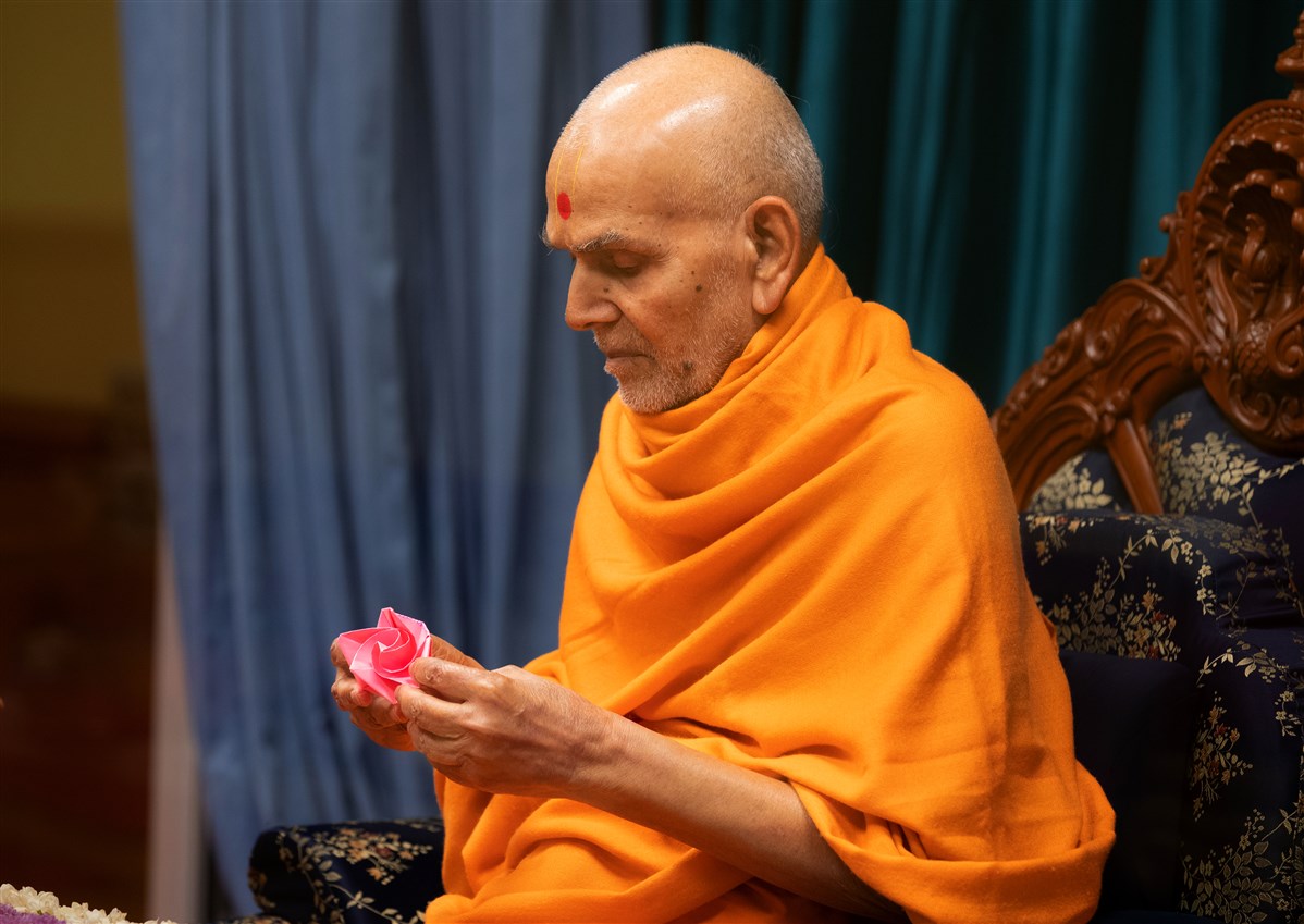 Swamishri observes an origami flower decoration