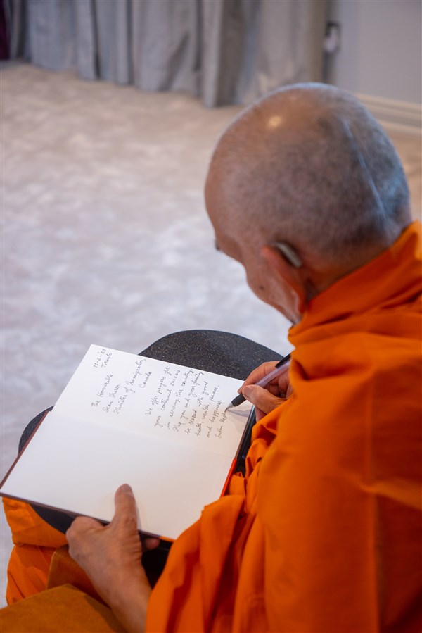 Swamishri pens personal blessings in the book gifted to Hon. Fraser