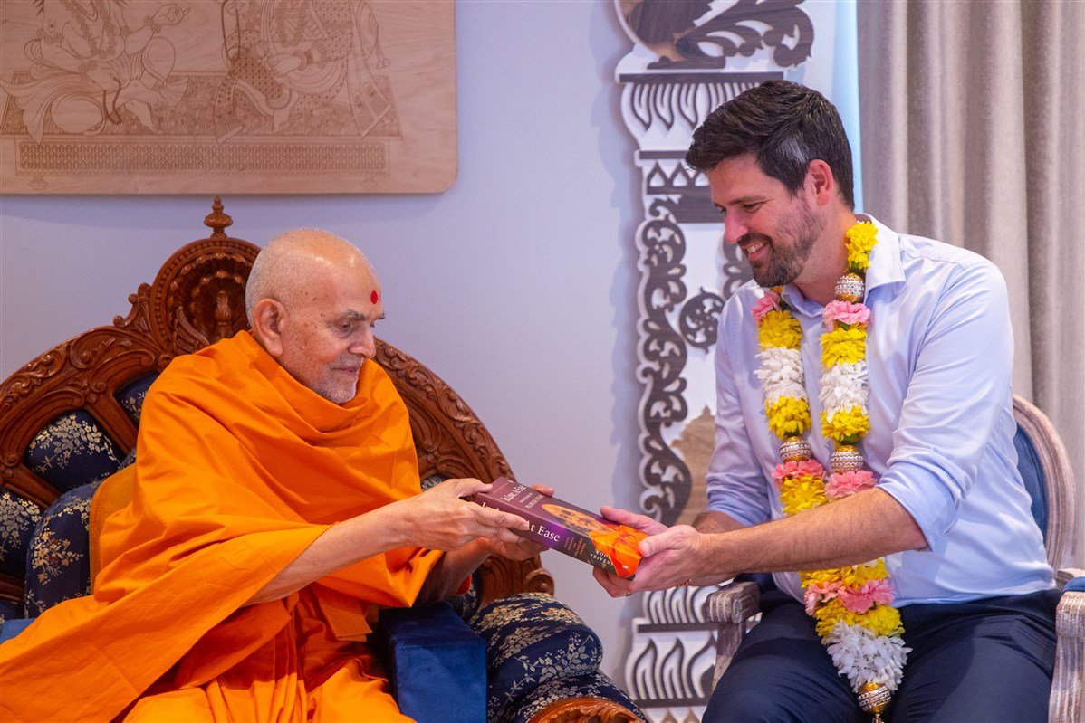 Swamishri presents Hon. Fraser with the book "In Love, At Ease" on Pramukh Swami Maharaj