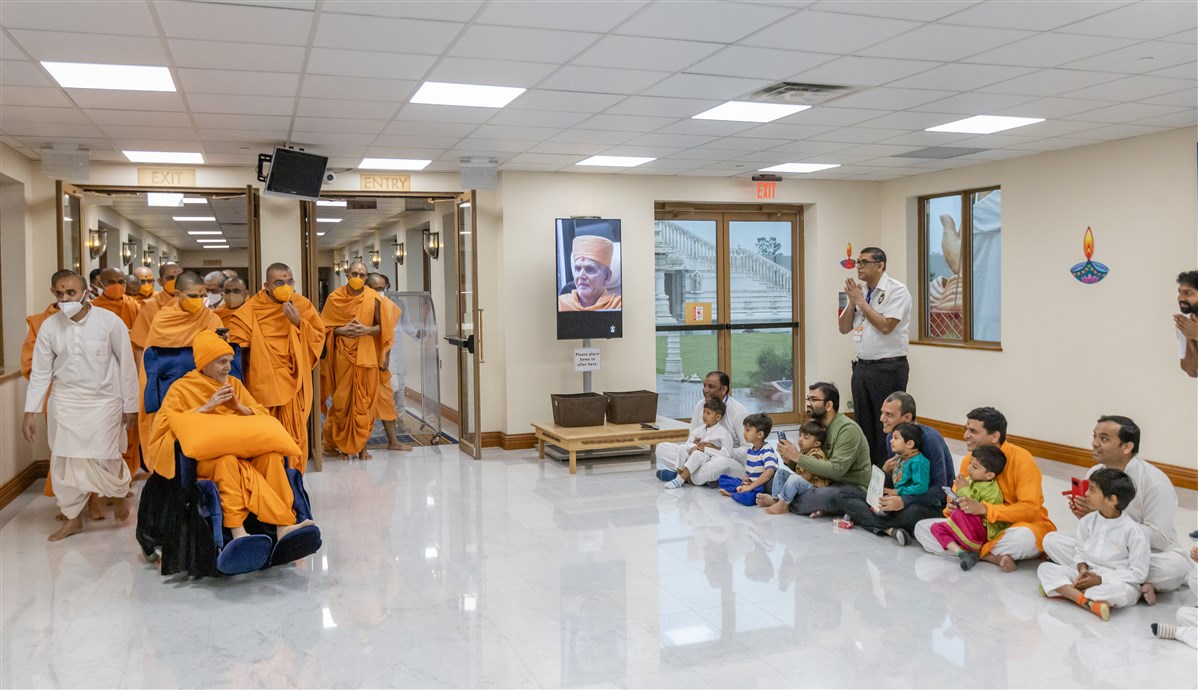 Swamishri bestows blessings upon devotees and their children as he proceeds to his morning puja