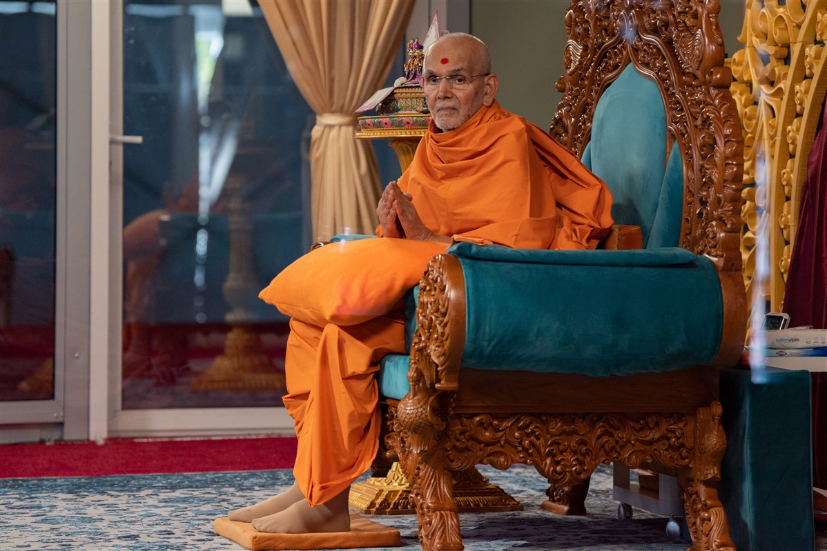 Swamishri patiently greets devotees, including those seated at his extreme left