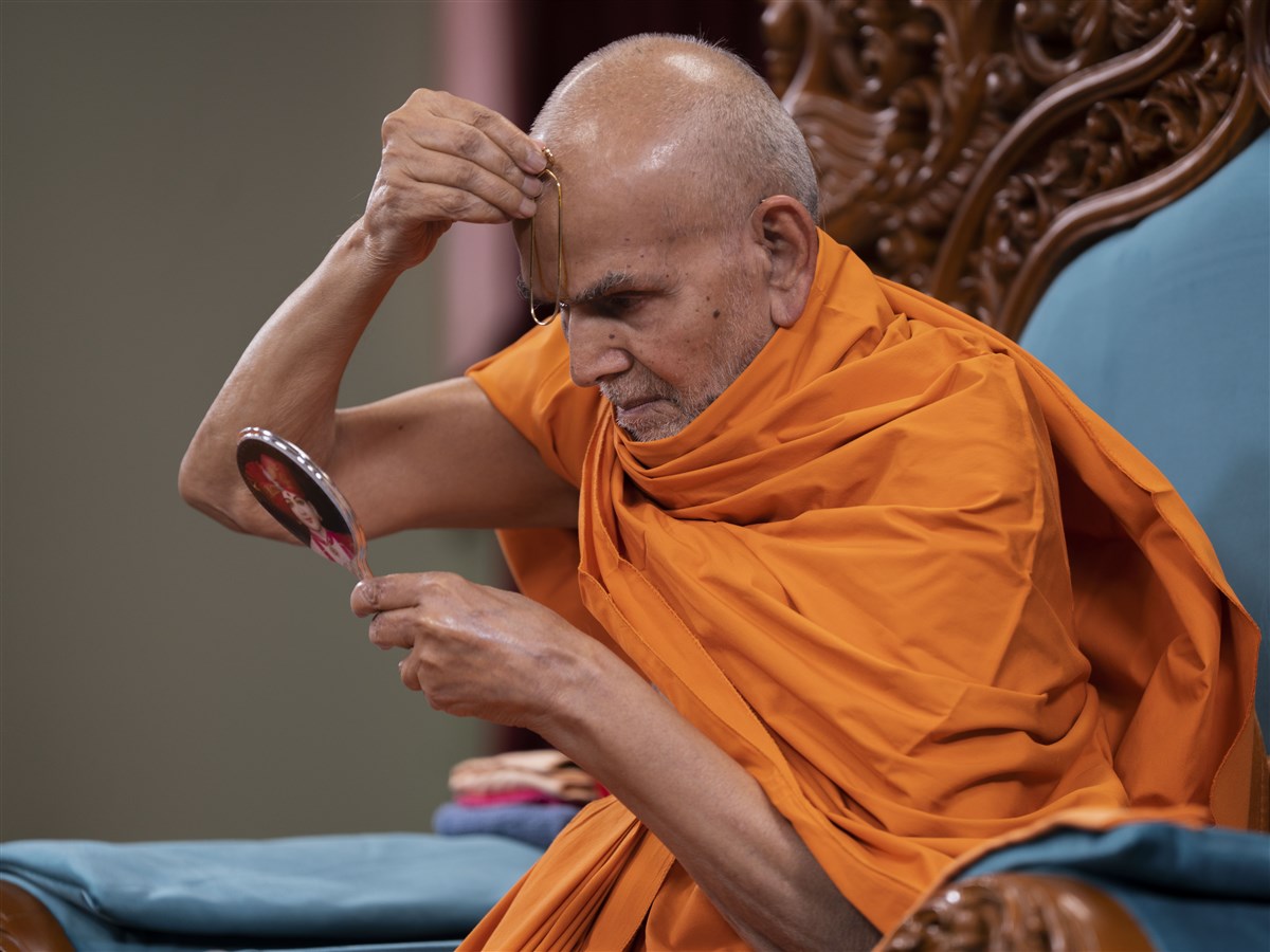 Swamishri commences his puja by applying a tilak on his forehead