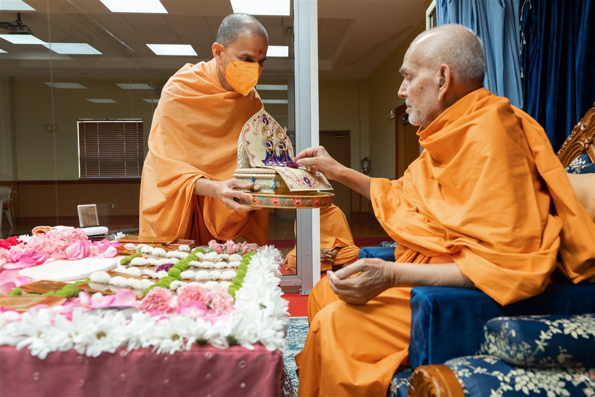 Swamishri offers a flower to Shri Harikrishna Maharaj and Shri Gunatitanand Swami Maharaj