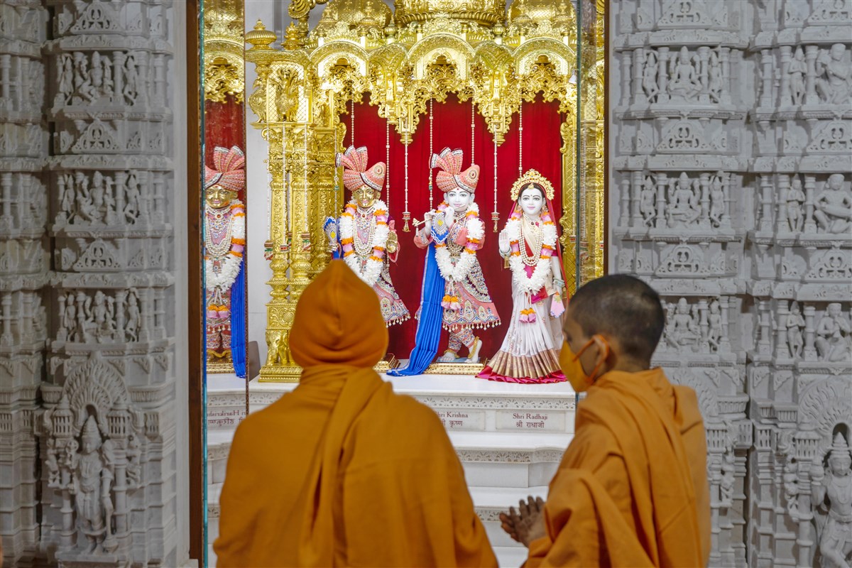 Swamishri engrossed in the darshan of Shri Harikrishna Maharaj and Shri Radha-Krishna Bhagwan