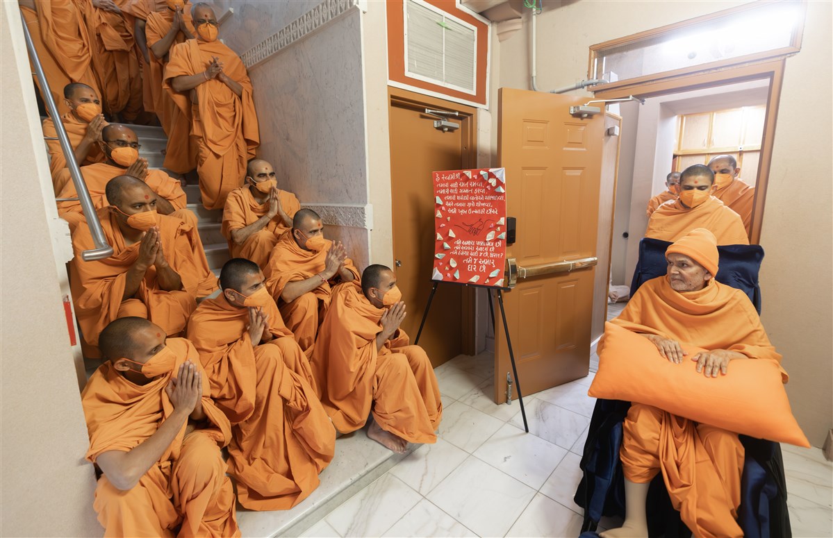 Swamis await on the staircase to catch a glimpse of Swamishri passing by