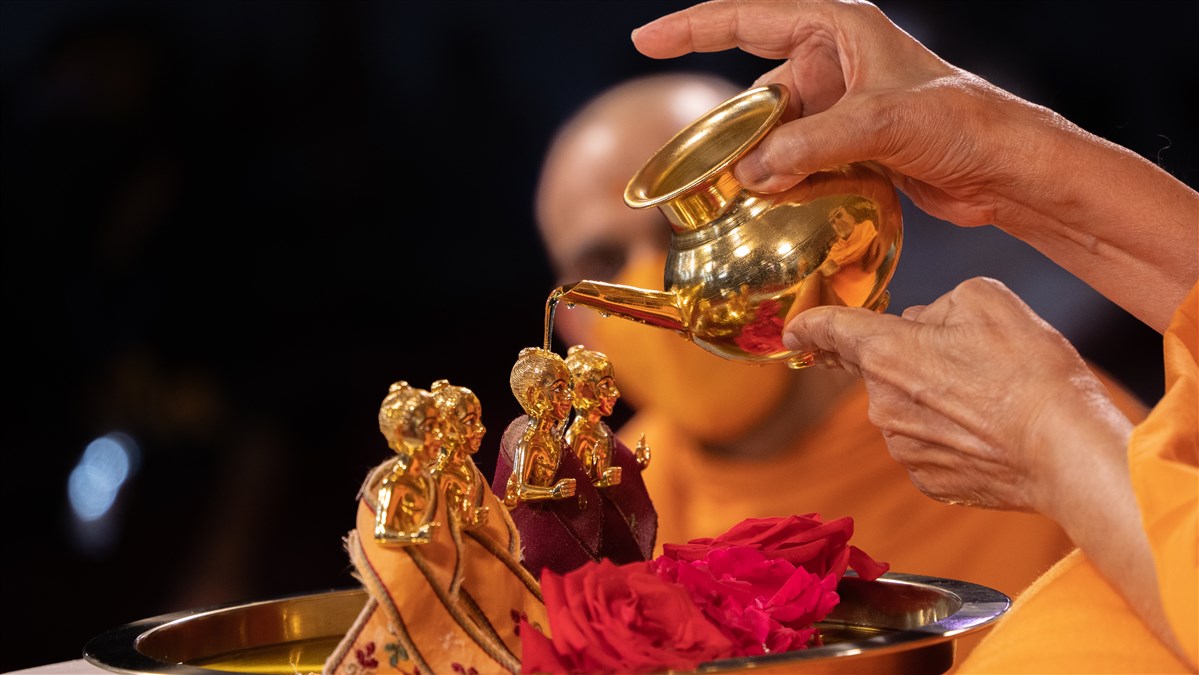 Swamishri performs the abhishek of the new murtis of  Shri Akshar Purushottam Maharaj