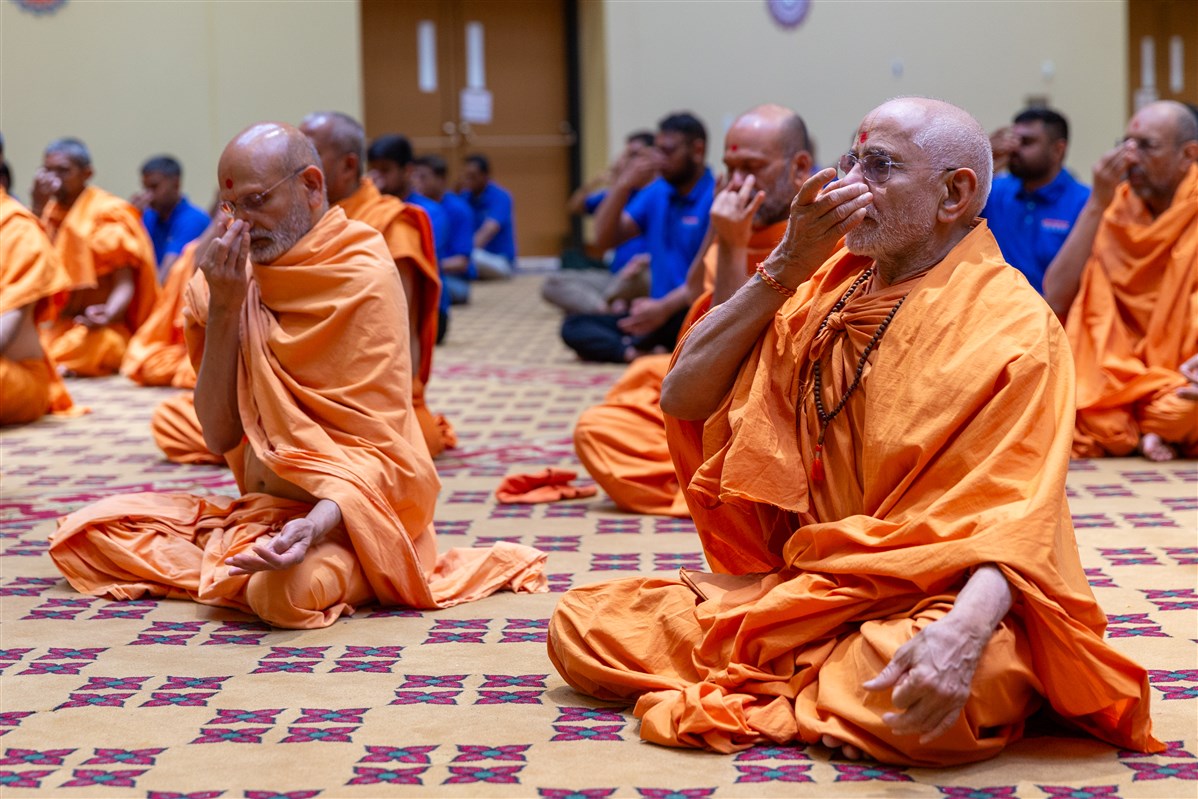 Swamis and devotees perform pranayama