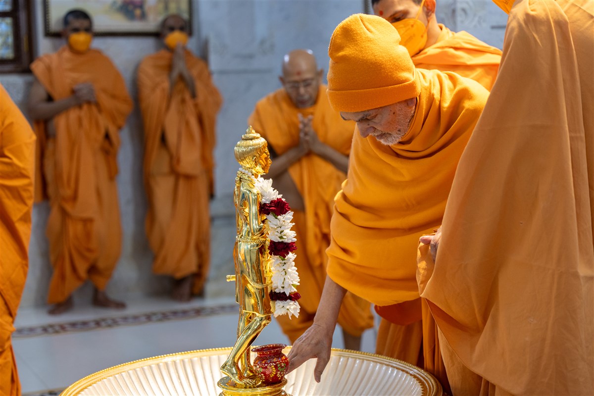 Swamishri reverentially touches the holy feet of Shri Nilkanth Varni