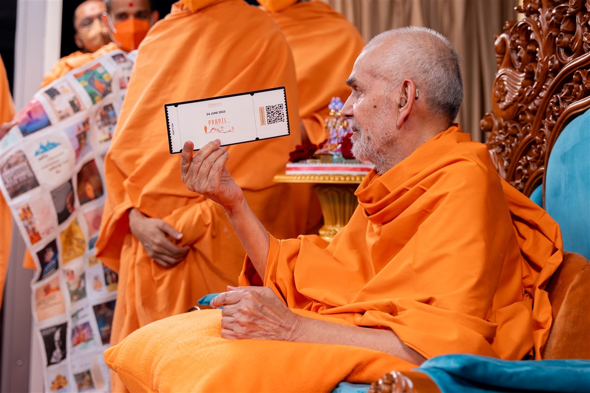 Swamishri sanctifies a pass for the evening Prapti Din assembly