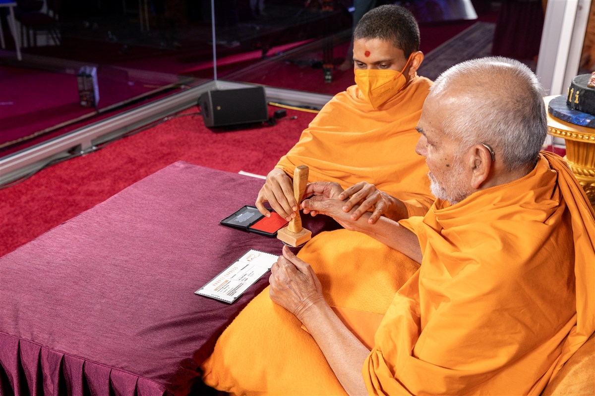 Swamishri stamps the evening assembly pass..
