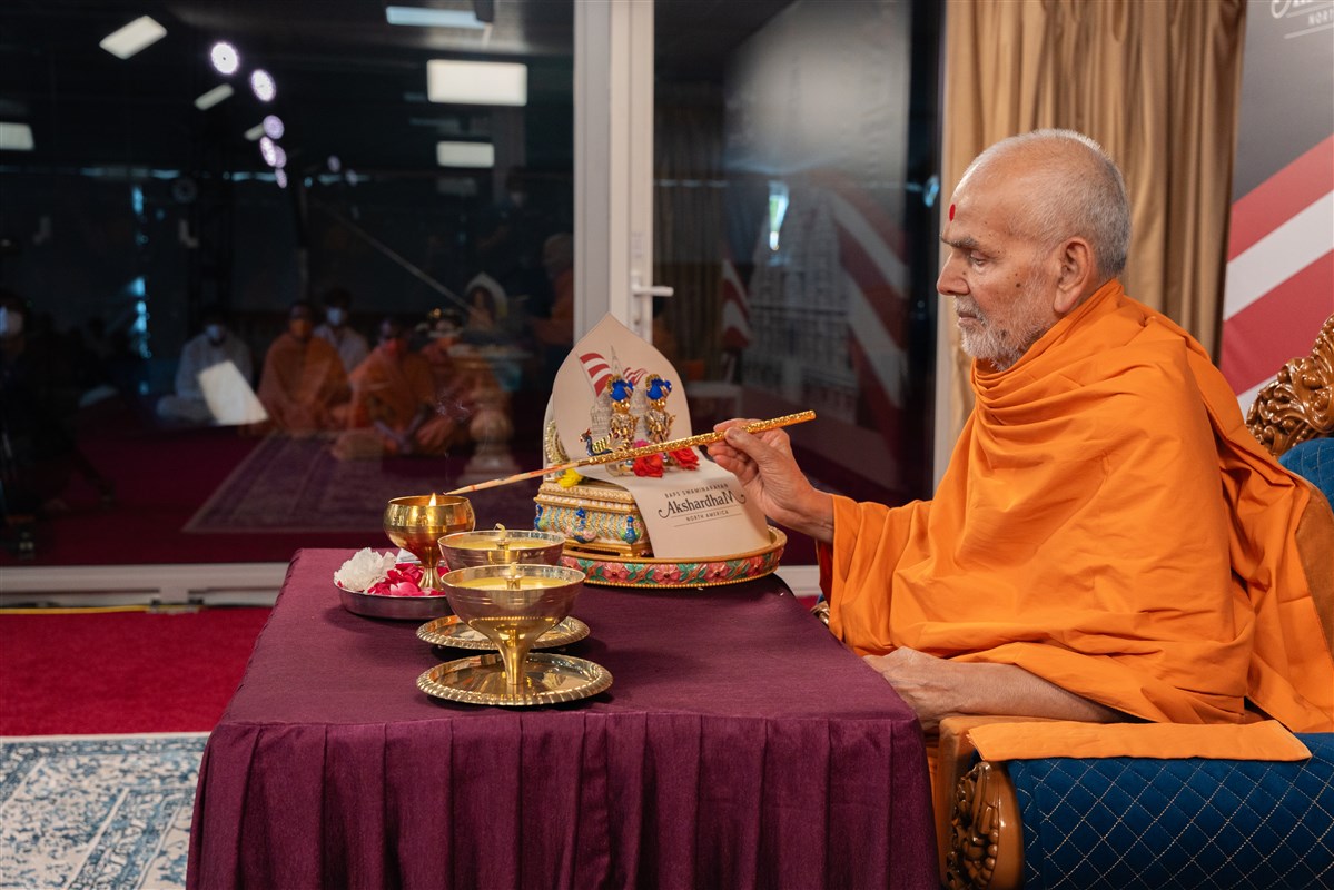 Swamishri takes flame from the lamp ignited using the sunrays and uses it to ignite two other lamps to mark the launch of the Festival of Inspirations to be celebrated in Robbinsville, New Jersey