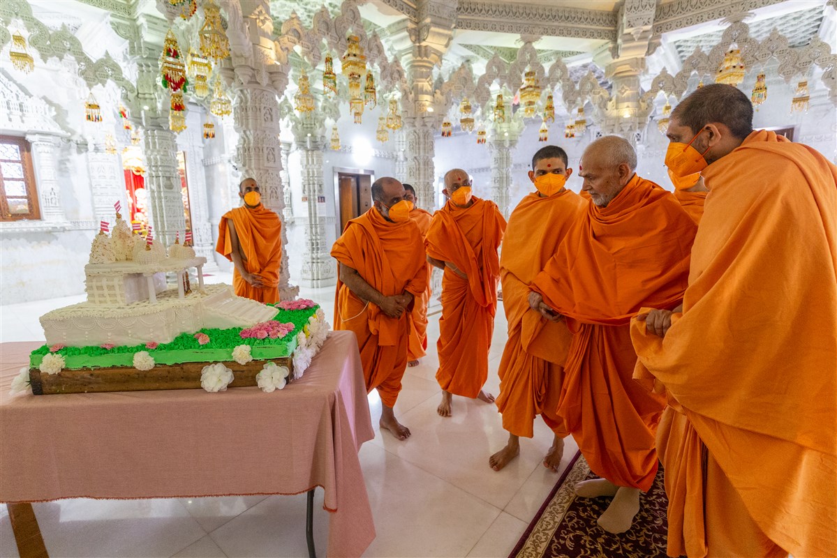 Swamishri observes a cake in the shape of a mandir