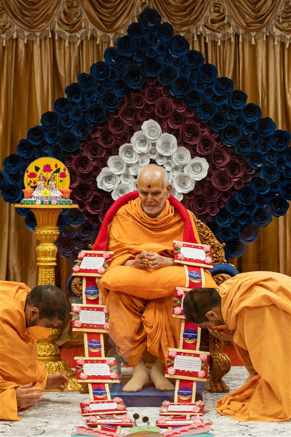 Swamis present Swamishri with a garland