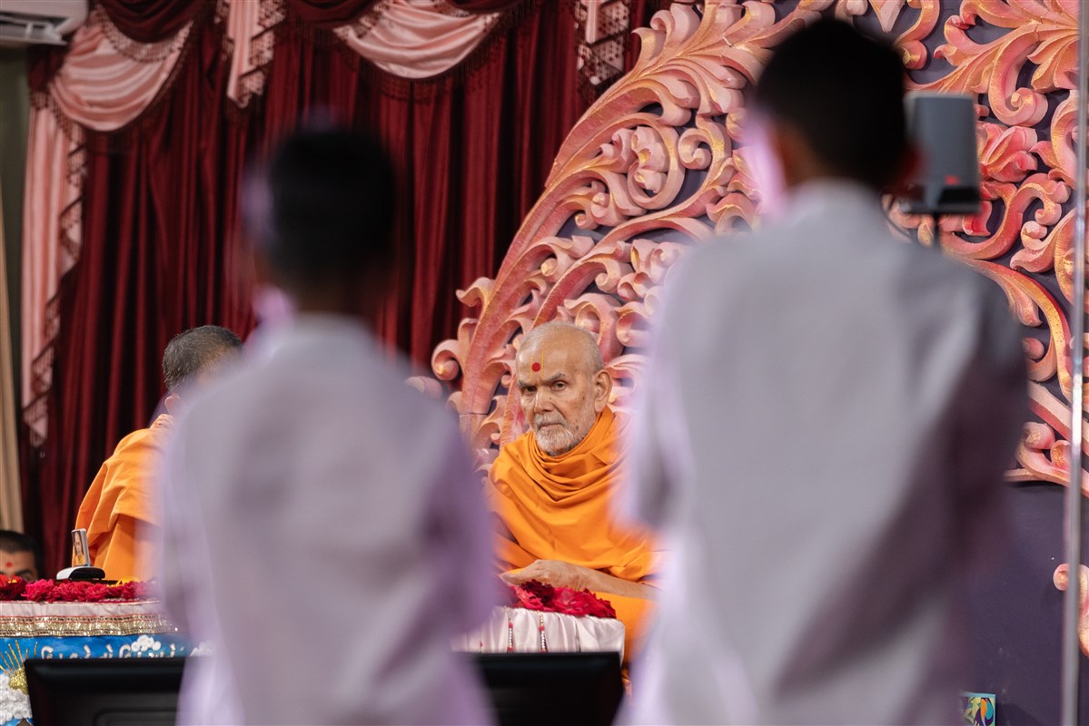 Swamishri glances at the children reciting scriptural passages in Swamishri's puja