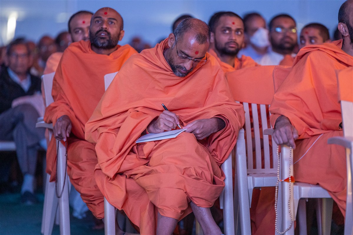 A swami takes notes during Swamishri's discourse