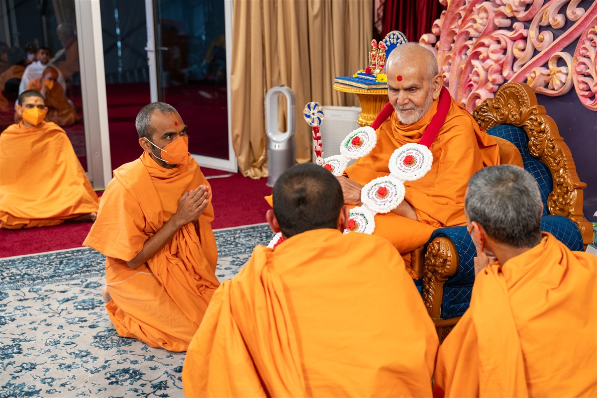 Swamis present Swamishri with a garland and chhadi