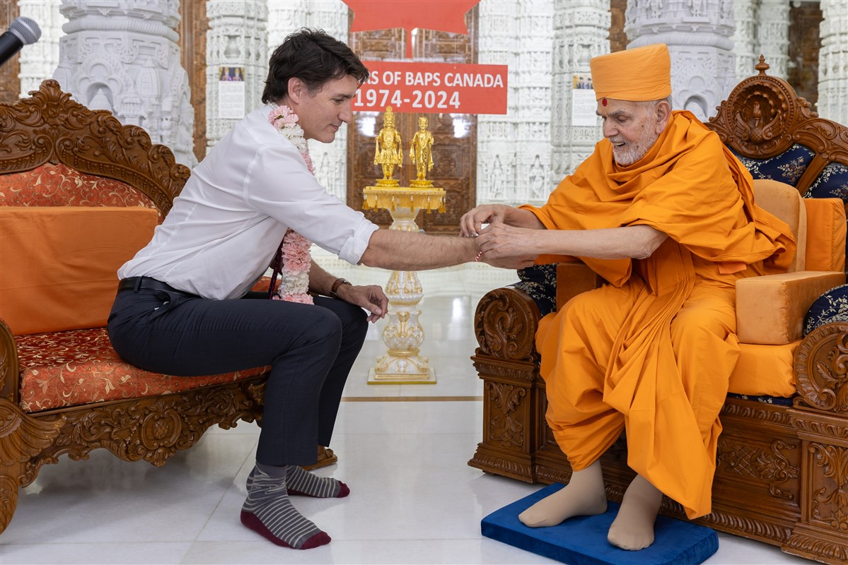 Swamishri ties a nadachadi on the wrist of Prime Minister Trudeau