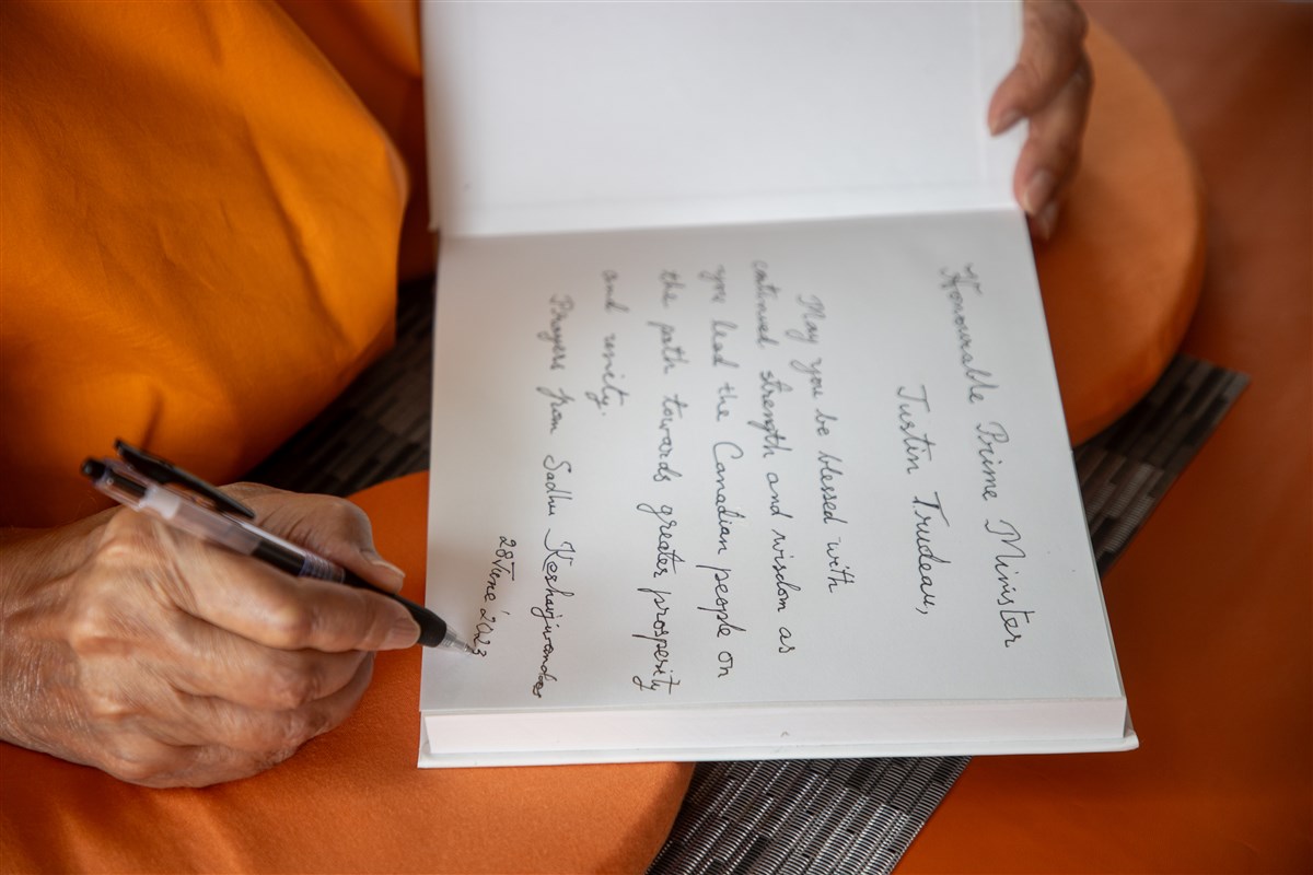 Swamishri inscribes personal blessings in a copy of 'Satsang Diksha', intended as a gift for the Prime Minister