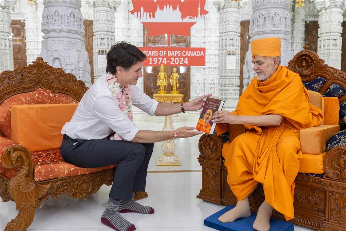 Swamishri presents Prime Minister Trudeau with the book "In Love, At Ease" on Pramukh Swami Maharaj