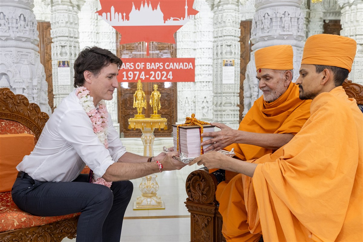 Swamishri presents a traditional manuscript of the Satsang Diksha to Prime Minister Trudeau