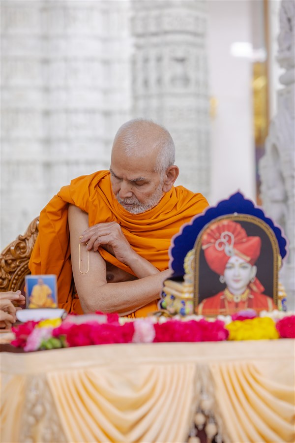 Swamishri applies a tilak on his right arm