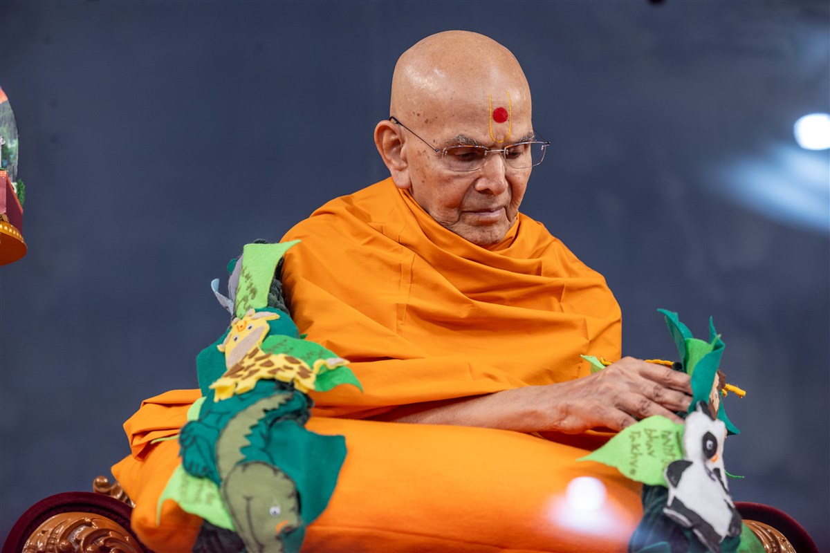 Swamishri observes a garland presented to him