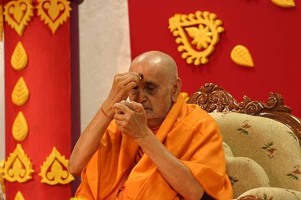 Swamishri applies chandlo to his forehead  